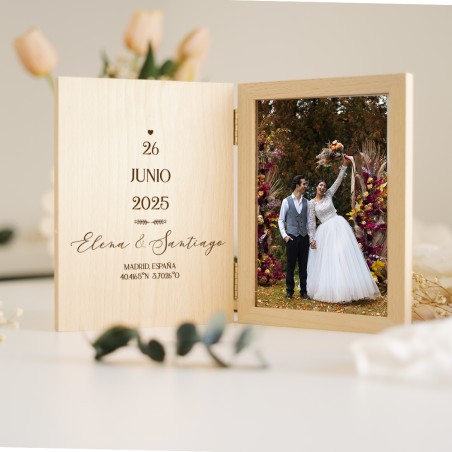 Vista del marco libro con la portada abierta, mostrando las iniciales de la pareja y la foto de la boda.