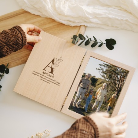 Vista del marco libro con la portada abierta, mostrando la personalización con iniciales y la foto de la pareja.